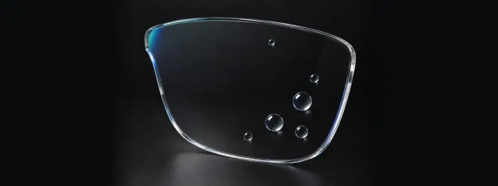 Lente transparente con antirreflejante y gotas de agua esféricas sobre el tratamiento hidrofóbico